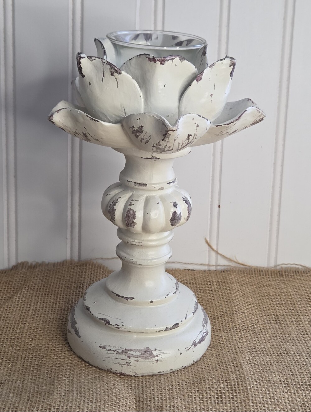 White candle stick holder features vintage-inspired flower shape and distressed